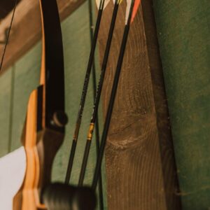 a-detailed-close-up-of-a-recurve-bow-with-arrows-positioned-against-a-wooden-wall