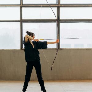 woman-practicing-archery-indoors-showcasing-focus-and-skill-with-a-bow-and-arrow